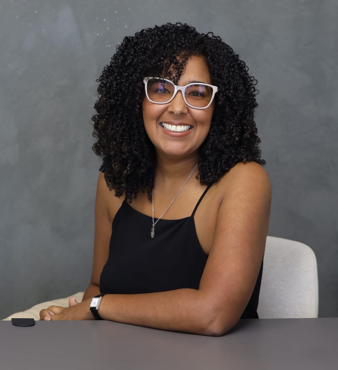 Linda De Jesús Casiano, Esq., sitting at her desk, smiling