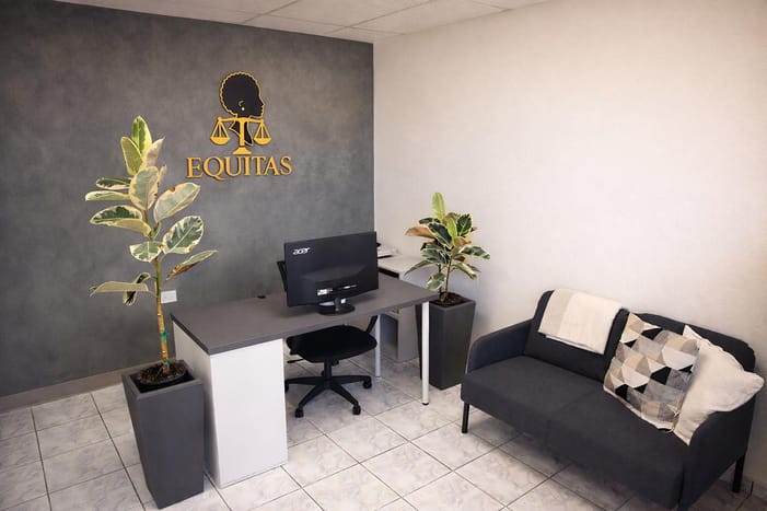 Reception with the gold Equitas logo, plants, and a sofa